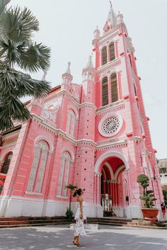 a woman standing in front of a pink church