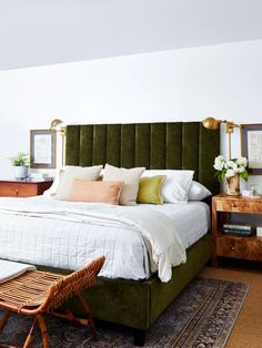 a bed with green headboard and pillows in a white room next to a wooden table