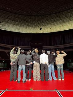 a group of people standing on top of a red floor