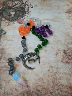 This set of prayer beads was made with Samhain in mind. This set of beads features colorful beads, a gemstone pendulum, and a silver-toned metal charm or charms. These prayer beads can be used as prayer or meditation beads, or for pendulum dowsing. These beads are made with Pagans, Wiccans, Witches, Druids, Heathens, and other Pagan groups in mind, but could be used by anyone who loves and has a deep reverence for the Earth. The beads are hand-wired using silver-toned stainless steel eye pins. T Spiritual Crystal Necklaces With Moon Charm For Festivals, Handmade Spiritual Crescent Crystal Necklace, Handmade Crescent Crystal Necklace With Spiritual Style, Handmade Spiritual Czech Glass Crystal Necklace, Spiritual Silver Crystal Necklace With 8mm Beads, Spiritual Czech Glass Natural Stone Crystal Necklaces, Pagan Prayer Beads, Pagan Prayer, Types Of Prayer