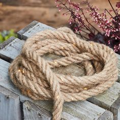 a rope that is sitting on top of a wooden box next to some purple flowers