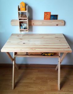 a wooden desk sitting on top of a hard wood floor next to a white wall