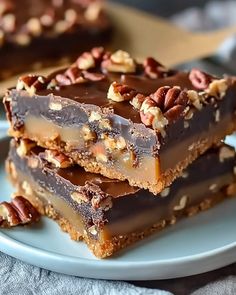 three pieces of chocolate pecan bar stacked on top of each other with walnuts