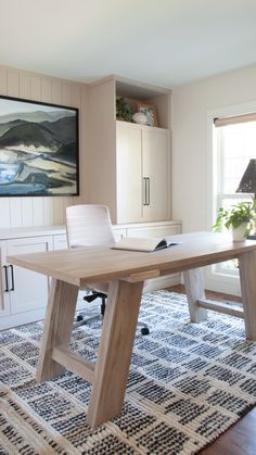 a large wooden table sitting in the middle of a living room next to a window