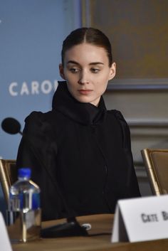 a woman sitting at a table in front of a microphone