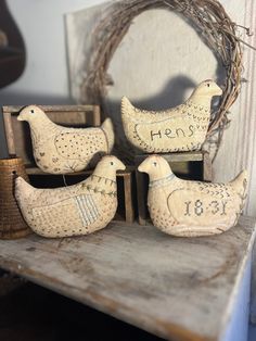 three wooden chickens sitting on top of a table next to a basket and a wreath