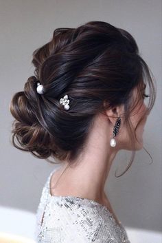 a woman with her hair up in a low bun and two pearls on the side