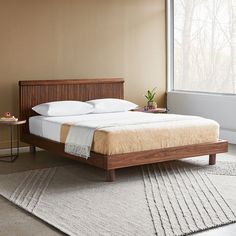 a bed sitting in a bedroom on top of a wooden floor next to a window