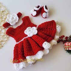 a crocheted dress and booties are laying next to a christmas tree ornament