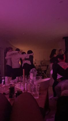 a group of people in a room with purple lighting on the ceiling and one person standing up