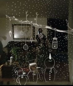 a window with christmas decorations drawn on the glass and people standing in front of it