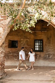 a man and woman holding hands under a tree