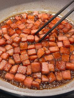 the food is being cooked in the wok with chopsticks and water on the side