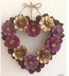 a heart shaped wreath with purple and gold flowers hanging on the wall in front of a white wall