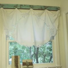 a window with white curtains and lace on the valance