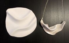 a white porcelain object sitting on top of a wooden table next to a silver chain