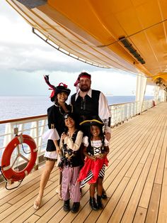 the family is posing for a photo on the deck of a ship while dressed up in pirate costumes