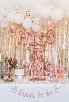 a table topped with pink and gold balloons next to a sign that says miss you's