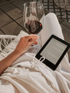 a person sitting on a chair with a glass of wine and an electronic device in their hand