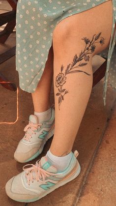 a woman sitting in a chair with her legs crossed and tattoos on the side of her leg