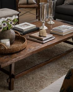 a coffee table with books, candles and flowers on it in front of a couch