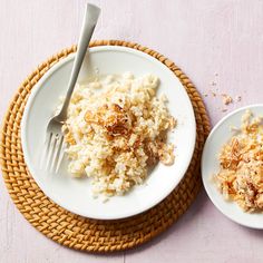 two white plates with rice and nuts on them next to a fork, knife and spoon