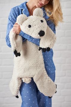 a woman is holding a knitted polar bear