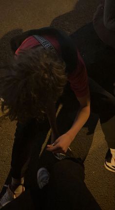 a person bending over on the ground with their cell phone