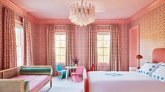 a bedroom with pink walls and curtains, colorful furniture, and a chandelier hanging from the ceiling