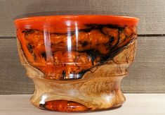 an orange and black bowl sitting on top of a wooden table next to a wall