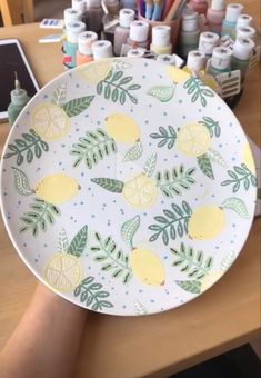 a plate with lemons and leaves painted on it sitting on a table next to some markers