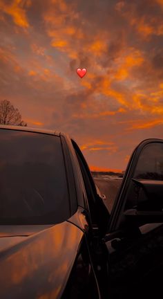 two cars parked next to each other with a red heart in the sky