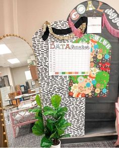 an office cubicle with a calendar on the wall and a plant in front of it