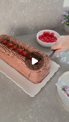 a person is cutting into a cake with cherries on the table next to it