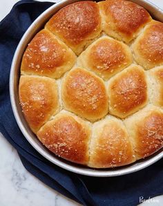 a pan filled with bread rolls on top of a blue cloth next to a knife