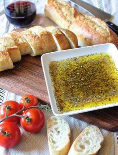 bread, tomatoes and olive oil sit on a cutting board next to some bread slices