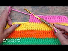 someone crocheting the side of a multicolored knitted blanket with two knitting needles