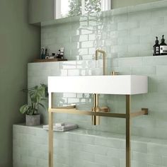 a white sink sitting under a window next to a green tiled wall in a bathroom