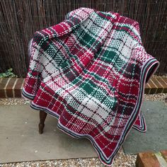 a red and white blanket sitting on top of a wooden bench