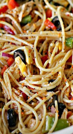 pasta with olives, peppers and chicken in a white bowl on a wooden table