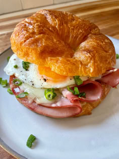 a bagel sandwich with ham, egg and cheese on it sitting on a plate