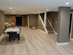 a living room with hard wood flooring and white piano in the center, next to stairs