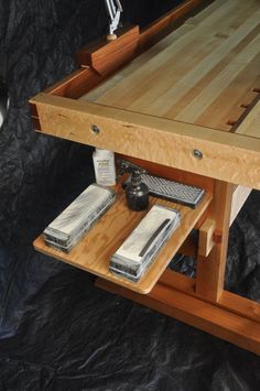 a workbench made out of wood with tools on the bottom and one drawer open