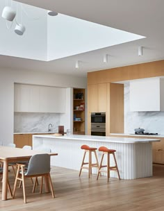 an open kitchen and dining area with wooden flooring, white cabinets and counter tops