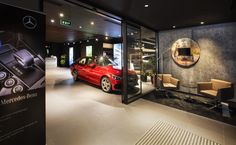 a red car is parked in front of a glass display case that says mercedes - benz