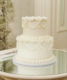 a white wedding cake sitting on top of a table next to a knife and fork