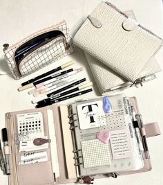 an open planner book with pens, pencils and other items in it on a table