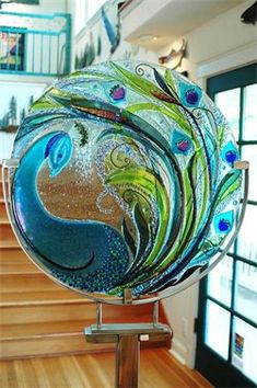 a decorative glass plate sitting on top of a wooden table next to a stair case