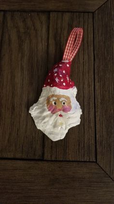 a santa claus ornament hanging on a wooden surface