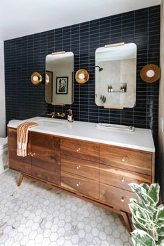 a bathroom with two sinks and mirrors on the wall next to a plant in front of it